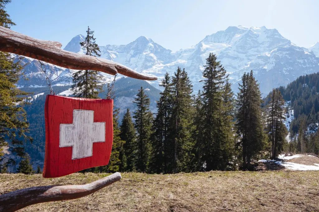 Schweizer Flagge vor Alpenkulisse – steht symbolisch für Aufenthalter Schweiz, die inmitten der Natur leben und arbeiten.