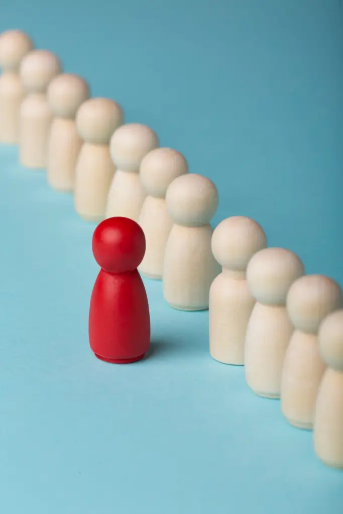 Eine rote Spielfigur steht einzeln zwischen zwei Reihen weißer Figuren – symbolisch für individuelle Berechnung und Entscheidungshilfe durch den Brutto-Netto-Rechner Schweiz.