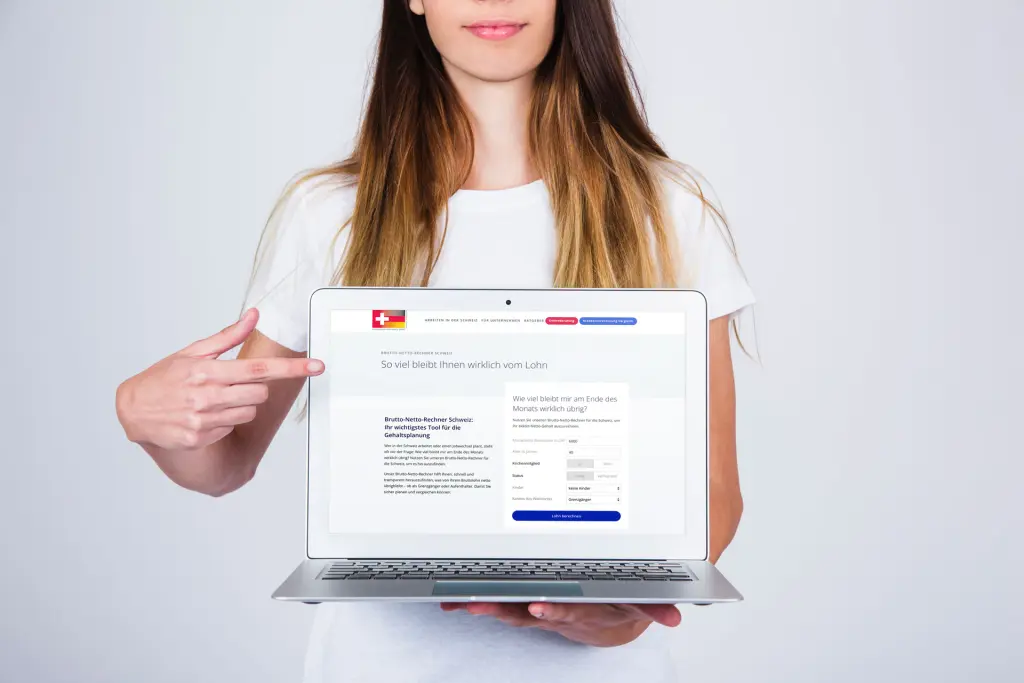 Frau zeigt auf Laptop mit dem Brutto-Netto-Rechner für die Schweiz zur Berechnung des Nettolohns für Grenzgänger und Aufenthalter.