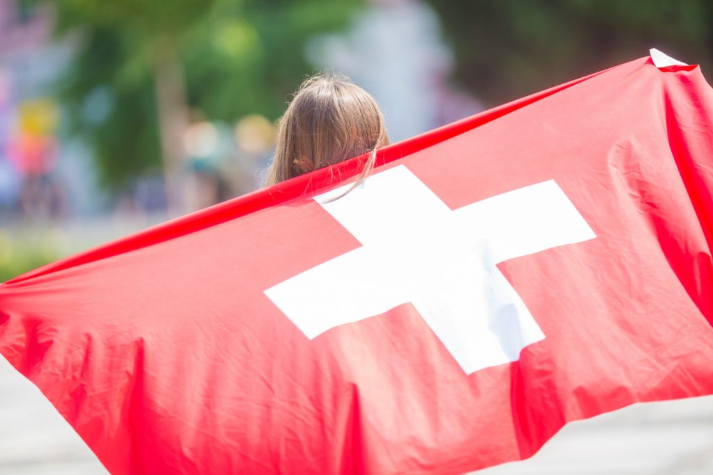 Mädchen mit Schweizer Flagge - so funktioniert die Aufenthaltsbewilligung Schweiz