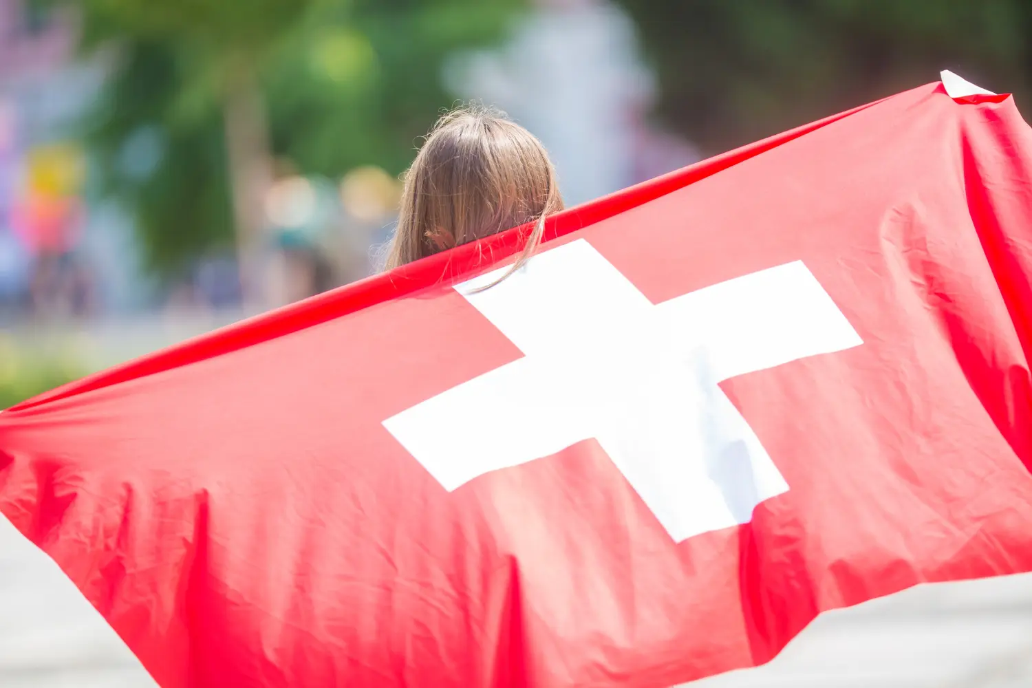 Mädchen mit Schweizer Flagge - so funktioniert die Aufenthaltsbewilligung Schweiz